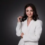 Elegancka kobieta w białej marynarce, zastanawiająca się, ile kosztuje portret u fotografa.