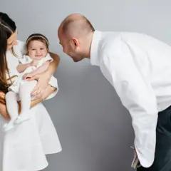 Rodzice z córeczką w białych strojach. Zastanawiasz się, ile kosztuje fotograf na chrzest?