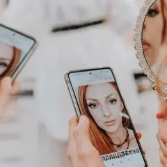 Kobieta ogląda swoje zdjęcia na telefonie, zastanawiając się, ile trwa wywołanie zdjęć u fotografa.