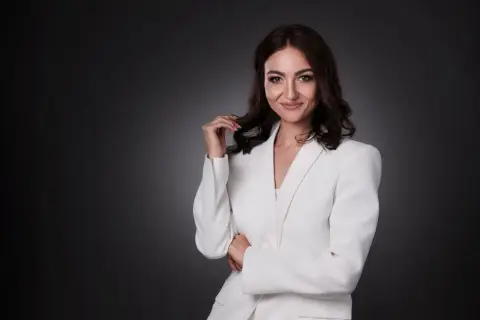 Elegancka kobieta w białej marynarce, zastanawiająca się, ile kosztuje portret u fotografa.