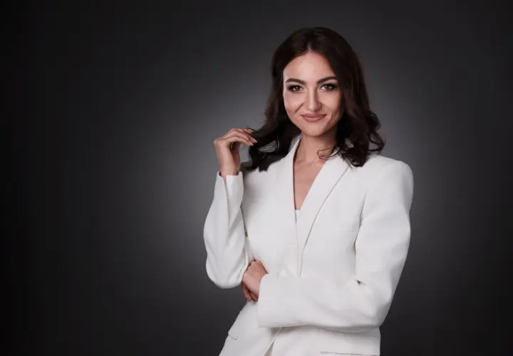 Elegancka kobieta w białej marynarce, zastanawiająca się, ile kosztuje portret u fotografa.