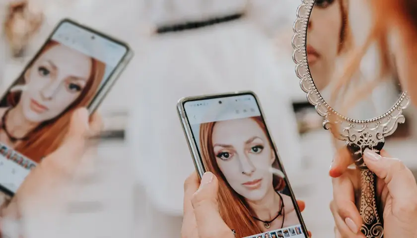 Kobieta ogląda swoje zdjęcia na telefonie, zastanawiając się, ile trwa wywołanie zdjęć u fotografa.