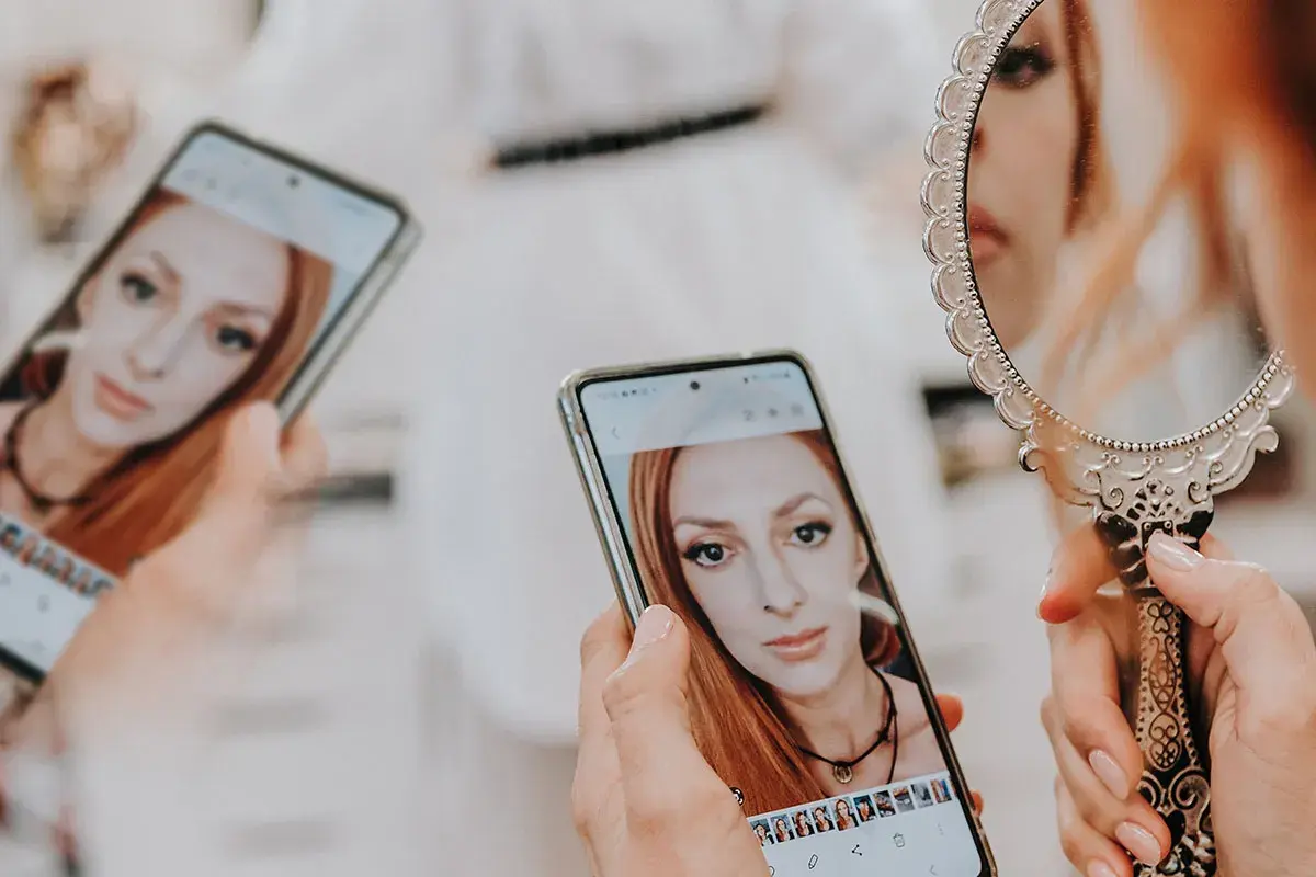 Kobieta ogląda swoje zdjęcia na telefonie, zastanawiając się, ile trwa wywołanie zdjęć u fotografa.