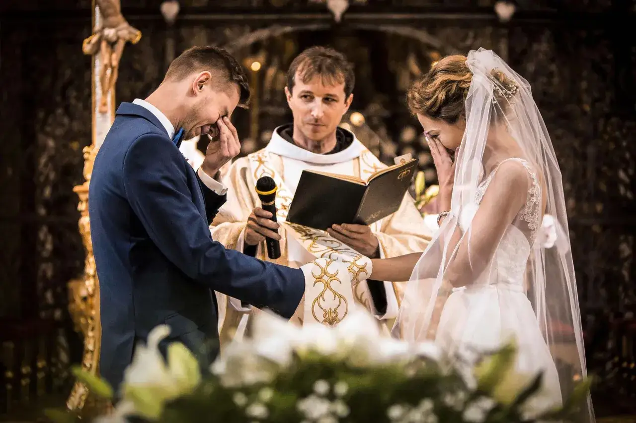 Wzruszająca chwila ślubu. Para młoda płacze ze szczęścia, ksiądz czyta przysięgę. Zastanawiasz się, ile kosztuje fotograf na wesele?
