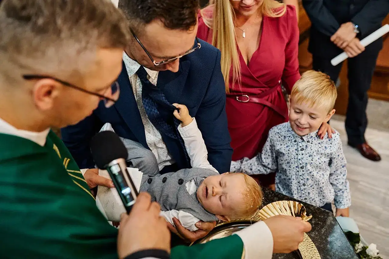 Chrzest dziecka, rodzice i ksiądz. Zastanawiasz się, ile kosztuje fotograf na chrzest? Uwiecznij ten ważny dzień!
