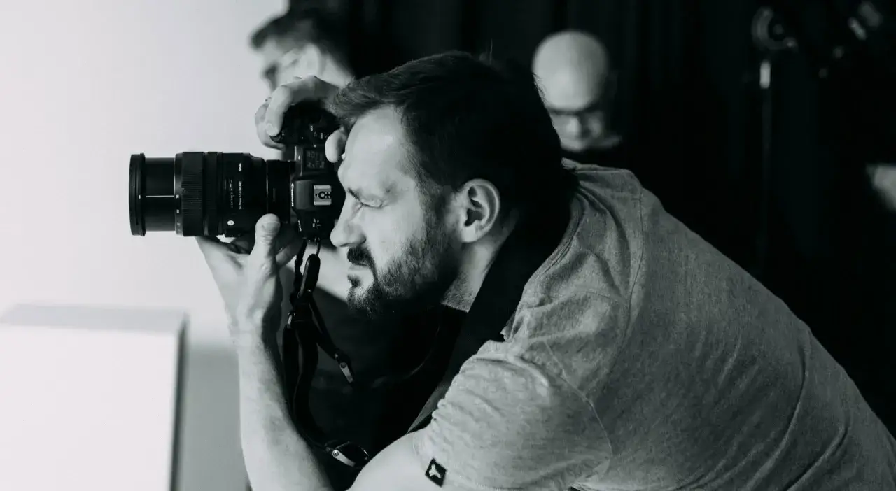 Fotograf z brodą robi zdjęcie. Czas oczekiwania na wywołanie zdjęć u fotografa zależy od jego obciążenia.
